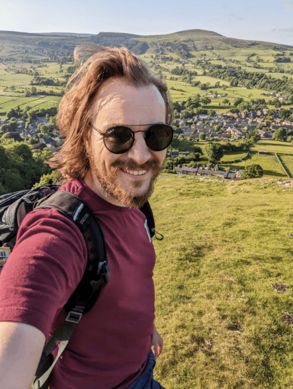 Portrait of Michal smiling on a green hill above small English town